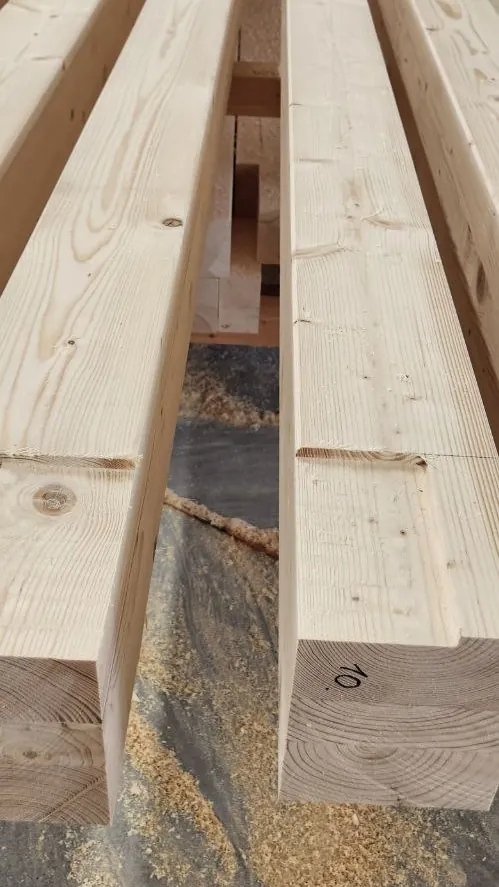 Two square-section timber beams on supports, one with part number 10 on its end, and wood shavings below