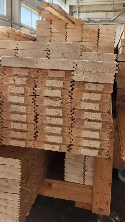Stacks of tongue-and-groove timber on a timber stand by the windows, seen end on