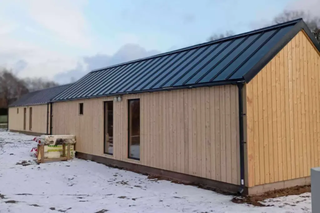 Log Cabin 11.8m x 4m with Cladding, 44 m², photograph of the back of a built house with two tall windows and a small one