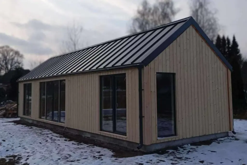Log Cabin 11.8m x 4m with Cladding, 44 m², photograph of a built house from the corner, in snow
