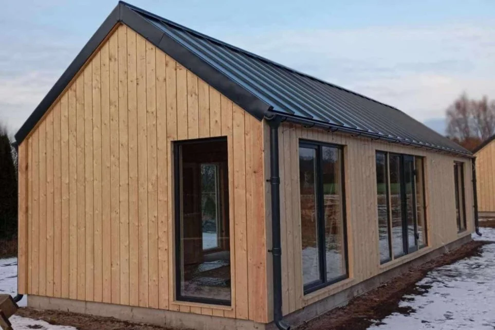 Log Cabin 11.8m x 4m with Cladding, 44 m², photograph of a gable end with a tall window and the door side, in snow